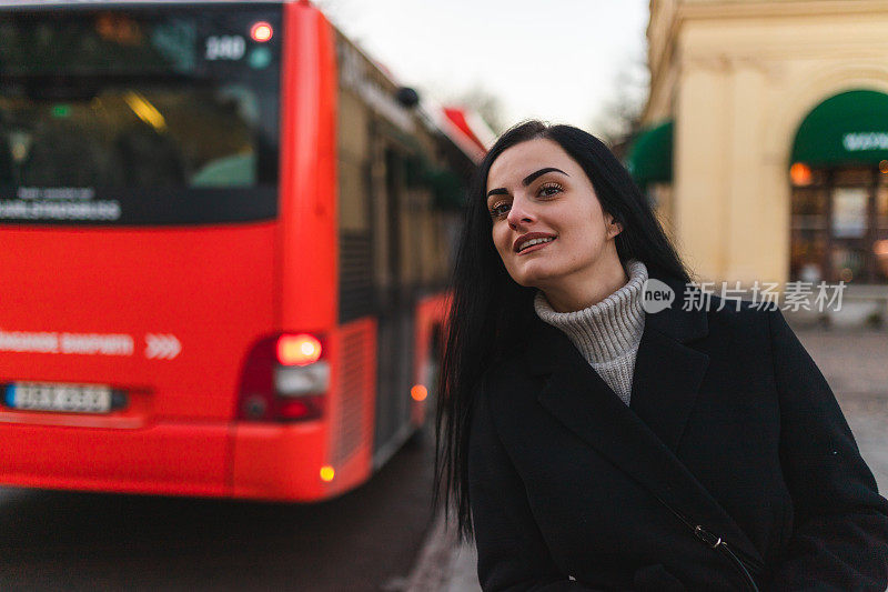 美丽的年轻女子在城市的公交车站等车