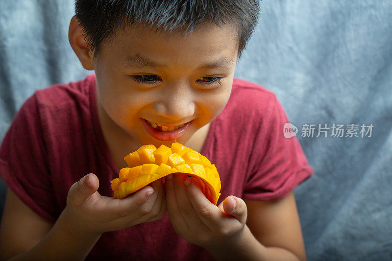 一个小男孩正在吃芒果