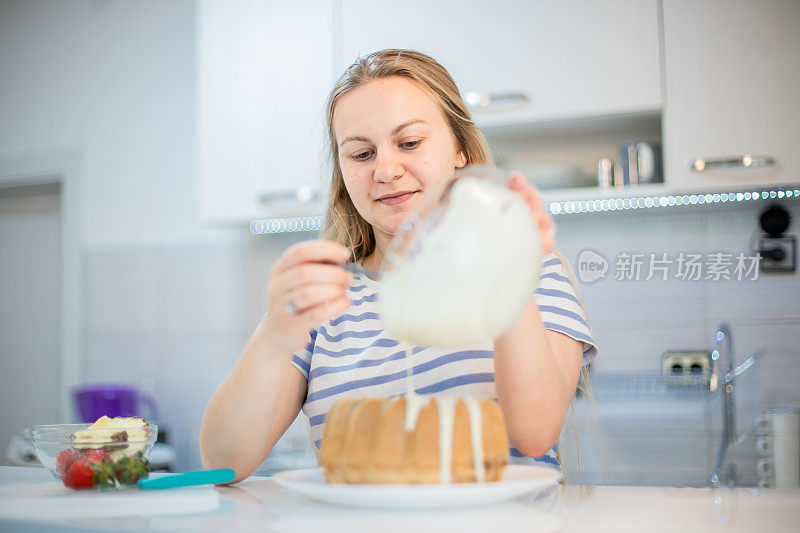 年轻女子正在装饰库格霍夫蛋糕，并把融化的白巧克力倒在上面