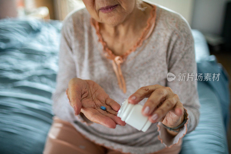 一个年长的女人在卧室里从药瓶里拿药