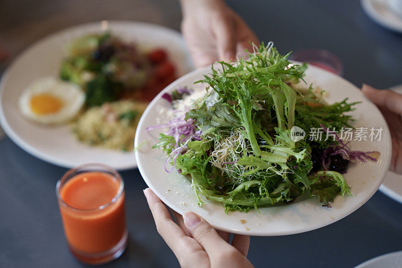 一个家庭在早餐时分享新鲜的蔬菜沙拉，突出了食物共享和外出就餐的概念。