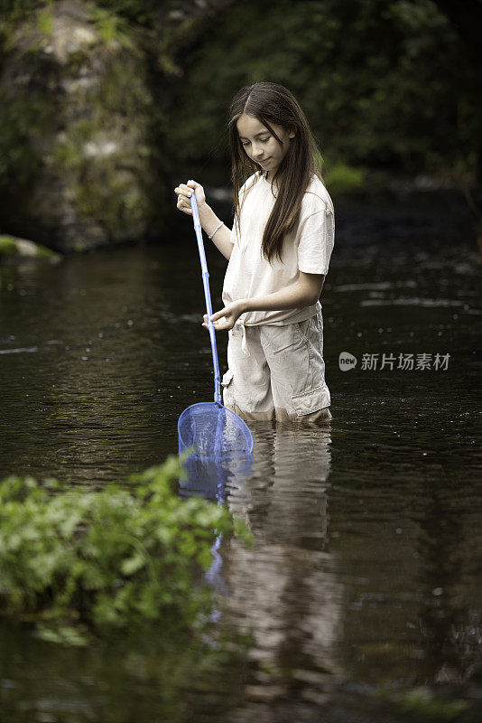 11岁的小女孩在小溪里拿着她的渔网