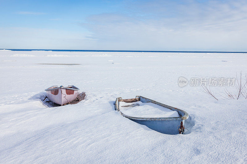 两艘渔船在波罗的海海滩上的雪地上