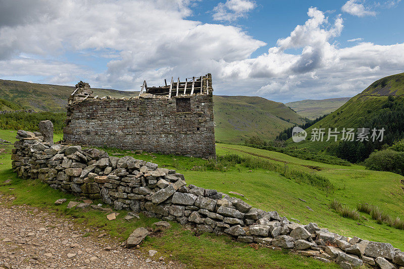 在英格兰约克郡山谷起伏的风景中，废弃的旧谷仓和毁坏的干石墙。