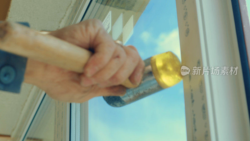 一个工人用橡胶锤敲打窗户的底图
