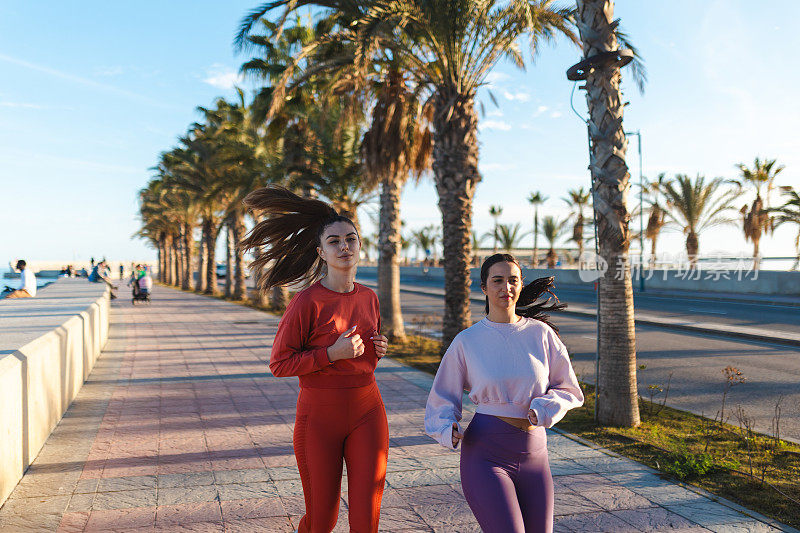 两个美女在西班牙马拉加的海滩上一起跑步