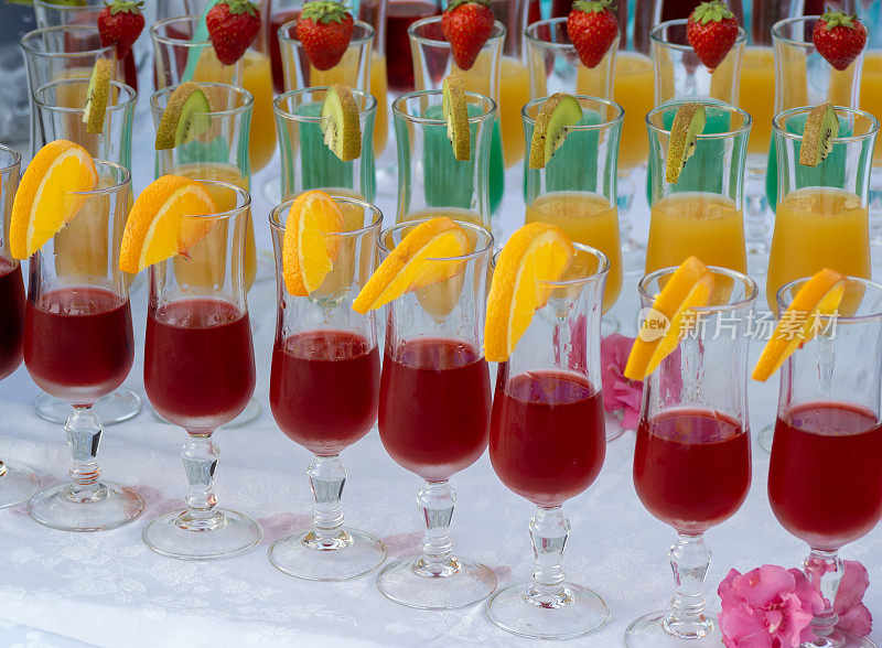 装有不同口味和颜色开胃酒的水晶酒杯。把水果放在杯子边上作为装饰品。不同颜色的果汁。夏天比赛