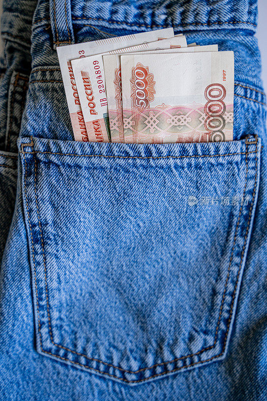 一张5000卢布的俄罗斯钞票放在蓝色牛仔裤的口袋里，从口袋里伸出来