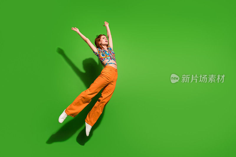 漂亮的年轻女孩的全身肖像跳跃飞空空间穿顶孤立在明亮的绿色背景