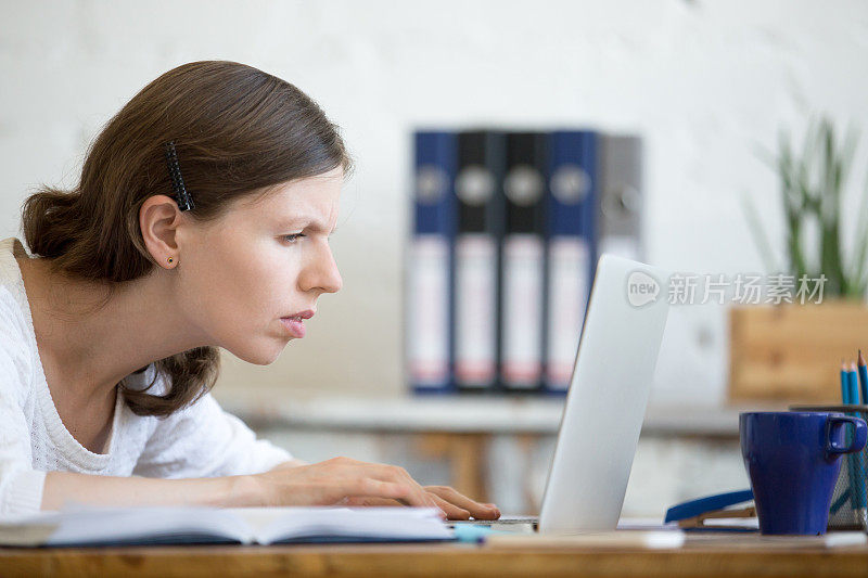 年轻关切的办公室妇女看着笔记本电脑