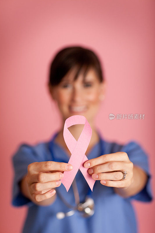 快乐的女护士手拿粉红乳腺癌意识丝带