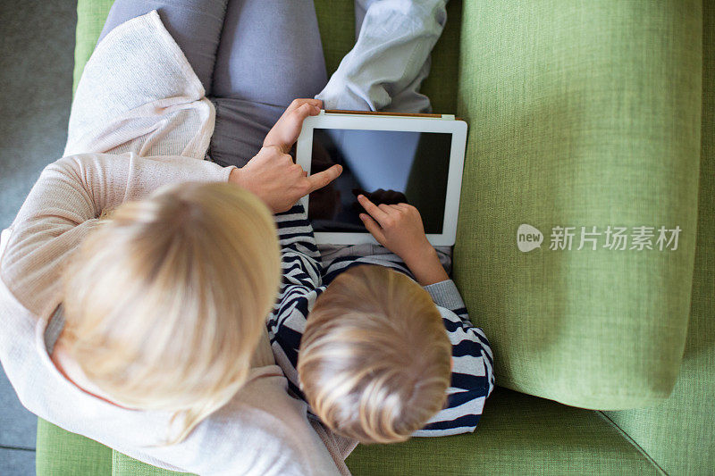 母亲和儿子在沙发上使用数码平板电脑