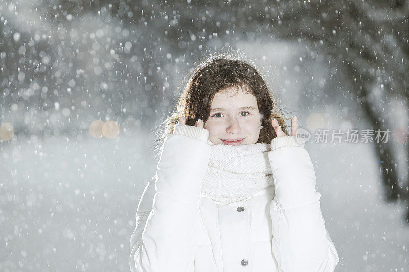 雪下穿着白色夹克的漂亮少女