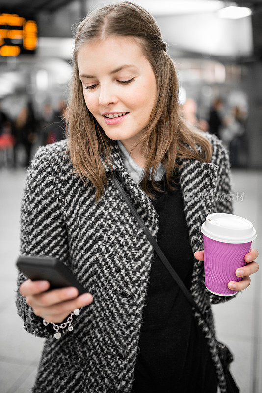 一个女人在地铁站里用智能手机