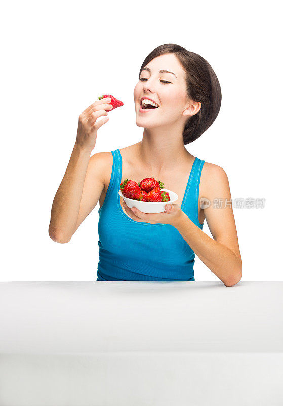 美丽的年轻女子在吃草莓
