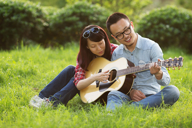 一对年轻夫妇在公园里弹吉他