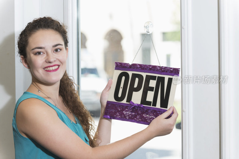 年轻女子在商店拿着开放的标志