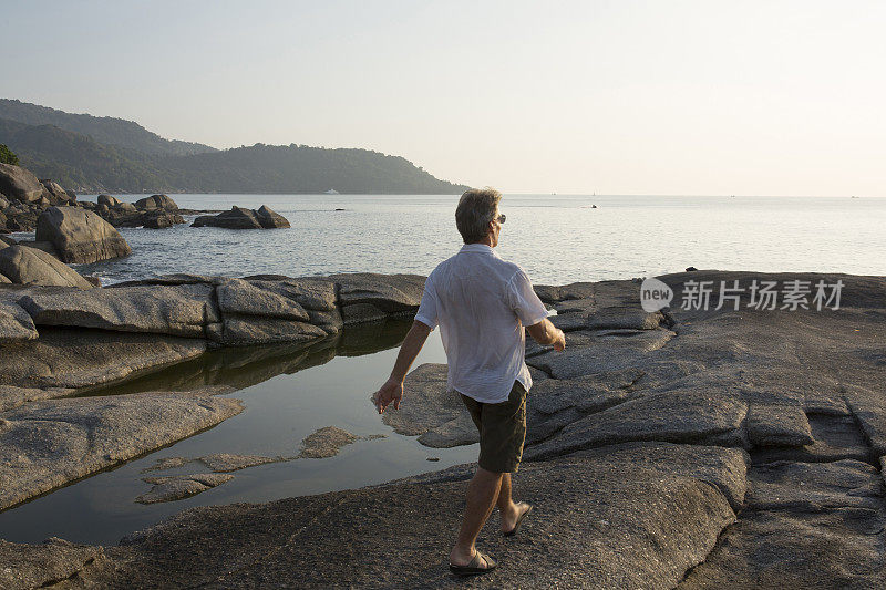 人沿着岩石走向大海，经过水池