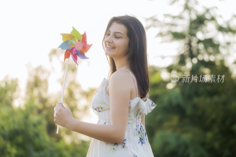 在油菜田里，一个女孩带着风力涡轮机