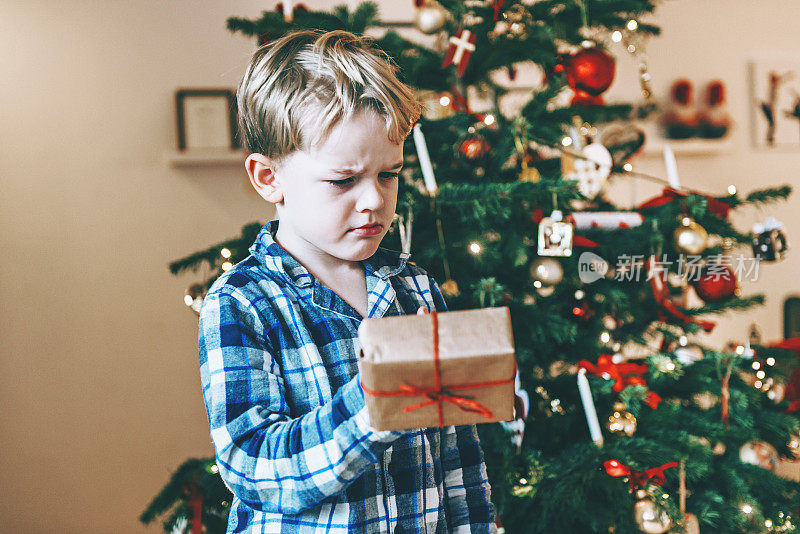 男孩在圣诞节早上收到礼物，看起来很不高兴