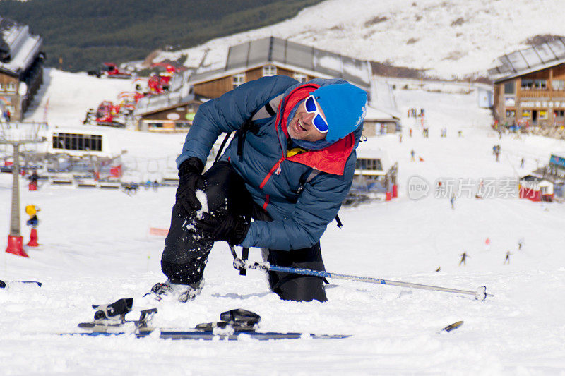 一名男子躺在雪地上滑雪摔伤了膝盖，疼痛难忍