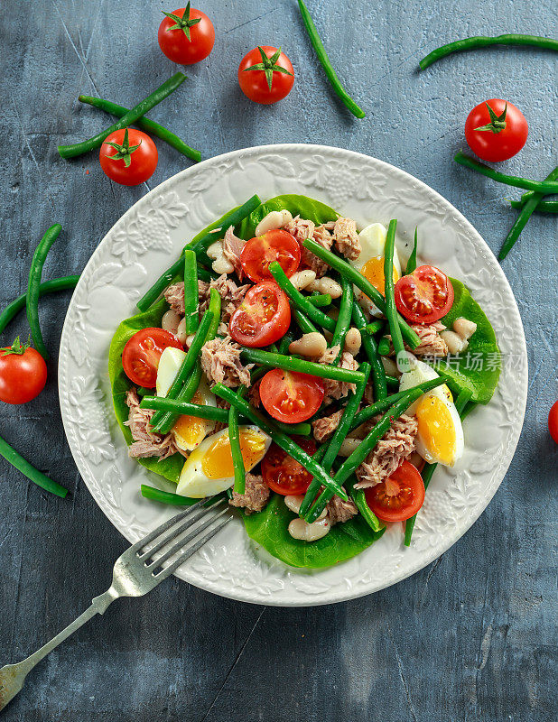 新鲜的金枪鱼青豆沙拉，鸡蛋，西红柿，豆子放在白色的盘子里。健康食品的概念