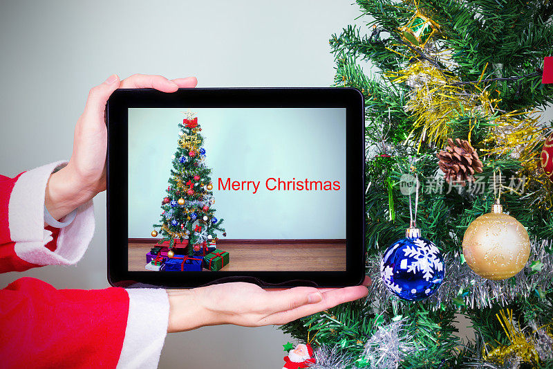 网上购物:圣诞树前手持数码平板电脑