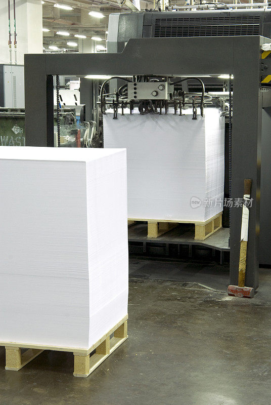 印刷厂的印刷机和成堆的纸张