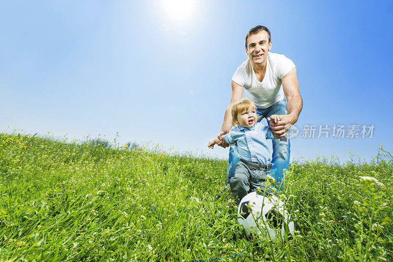 爸爸和他的小男孩在踢足球。