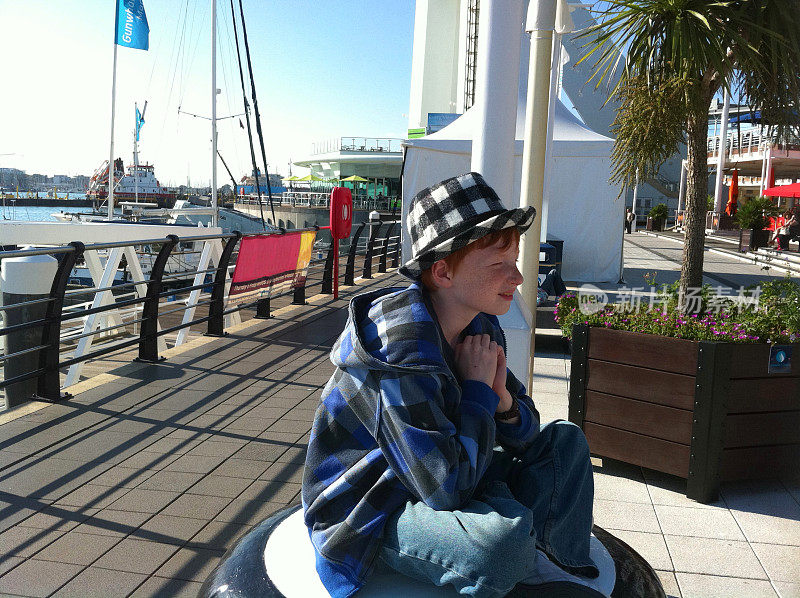 汉普郡朴茨茅斯的Gunwharf码头上坐着一个男孩