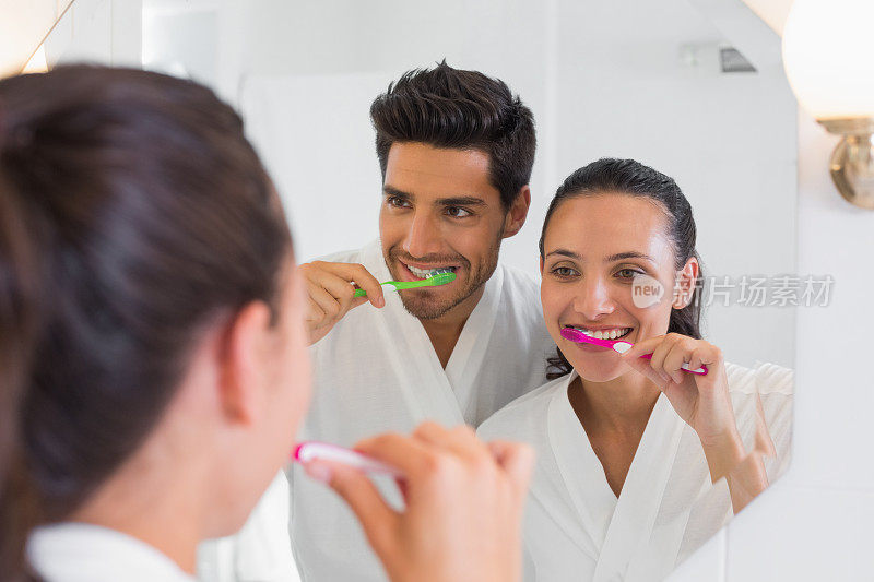 一对可爱的情侣在浴室镜子前刷牙