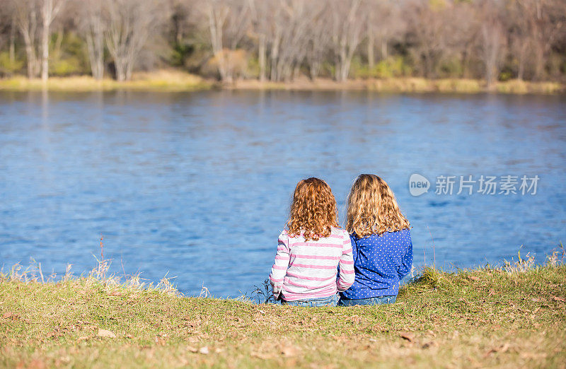 坐在密西西比河岸边的两个年轻女孩