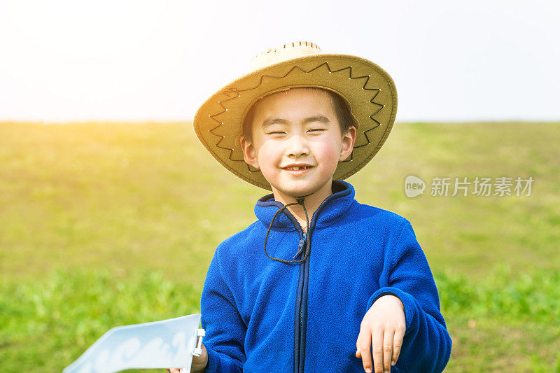 亚洲男孩带着纸飞机在草地上