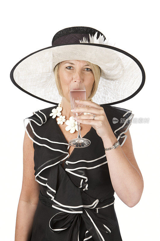 时尚的女人戴着帽子喝粉红色的香槟在白色的背景