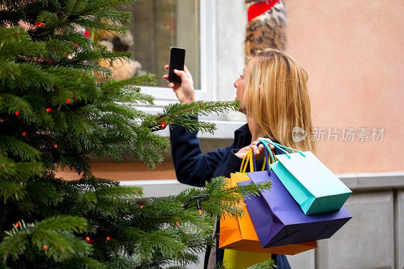 一个为圣诞节购物的女人拍下了窗户手机的照片