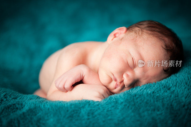 刚出生的男婴安静地睡在柔软的毯子上
