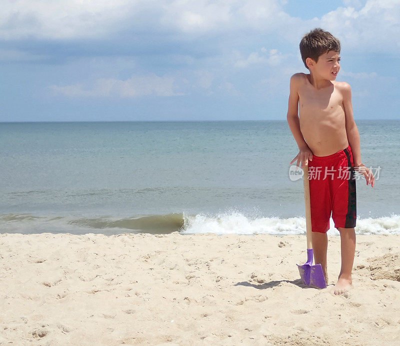 男孩拿着铲子在海滩上
