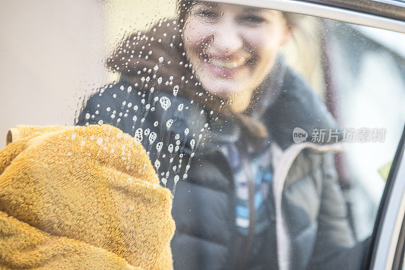 年轻快乐的女人在擦车窗