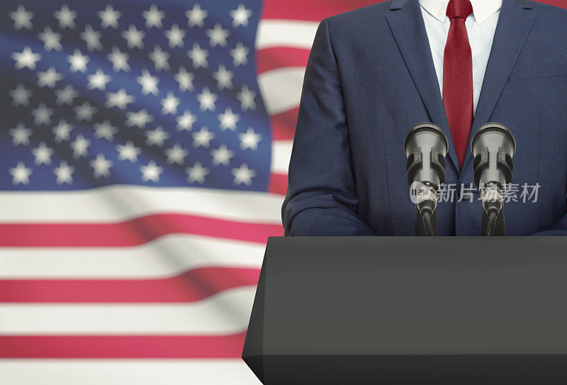 商人或政治家站在带有国旗背景的讲坛后发表演讲-美国