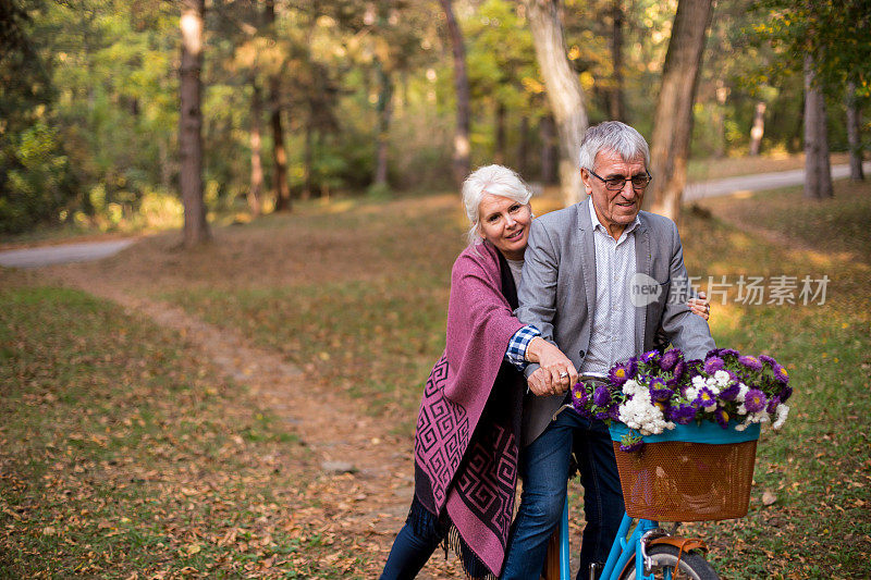 活跃的老年人在秋天的大自然中骑自行车。他们放松的户外。