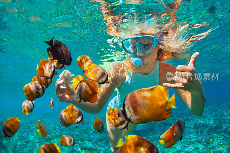年轻女子浮潜与珊瑚礁鱼类
