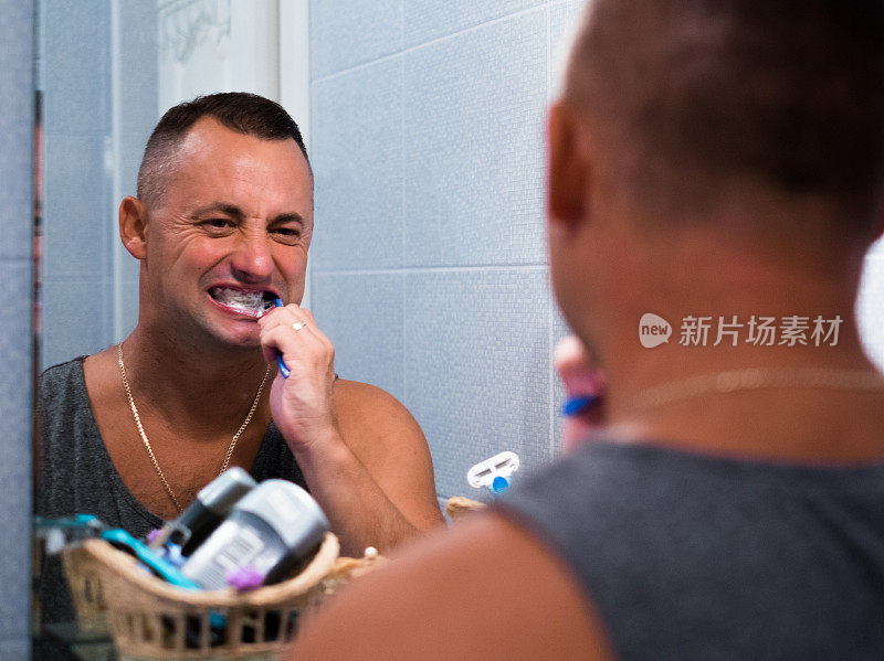 拿着牙刷在浴室刷牙的男人
