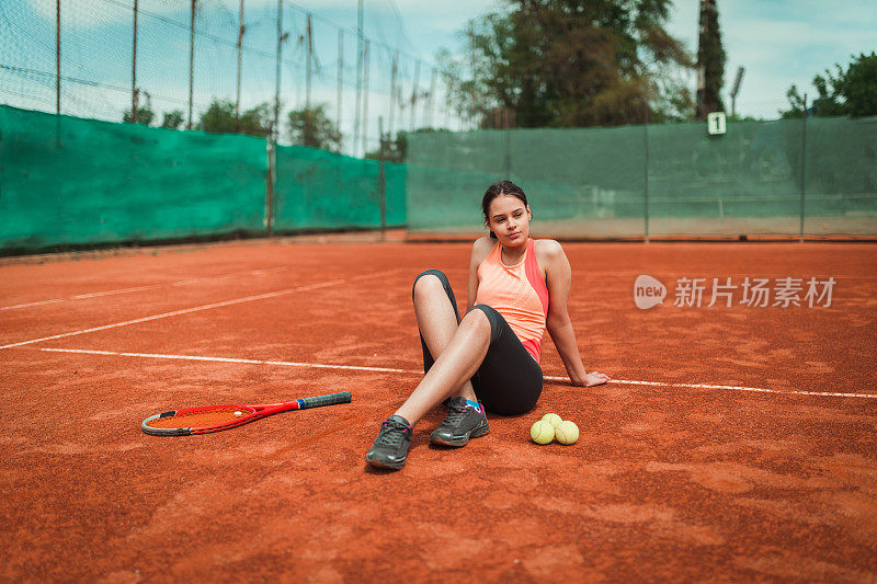 女子网球运动员在训练后坐在红土场上