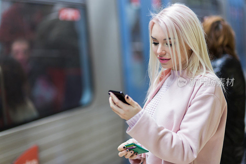 在地铁上使用智能手机的优雅女性