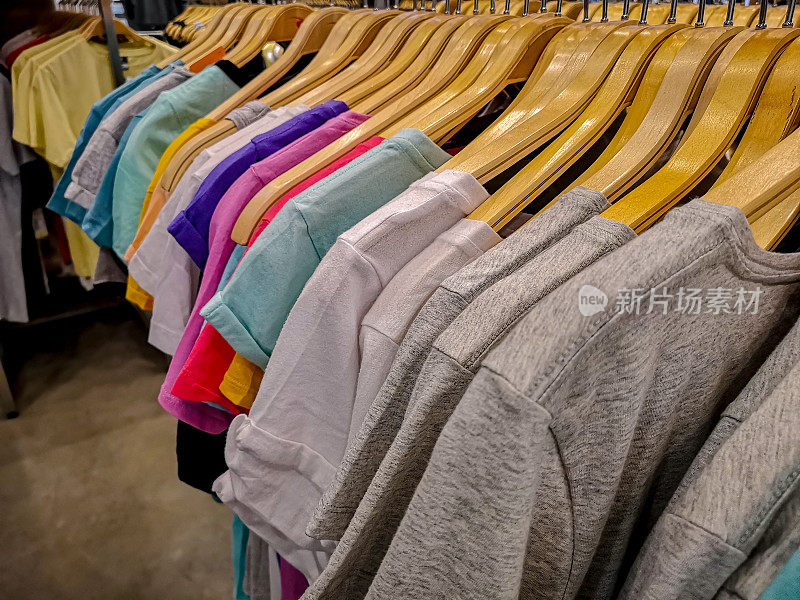 在一家高街的女装商店里，一排排五颜六色的t恤挂在衣架上出售。