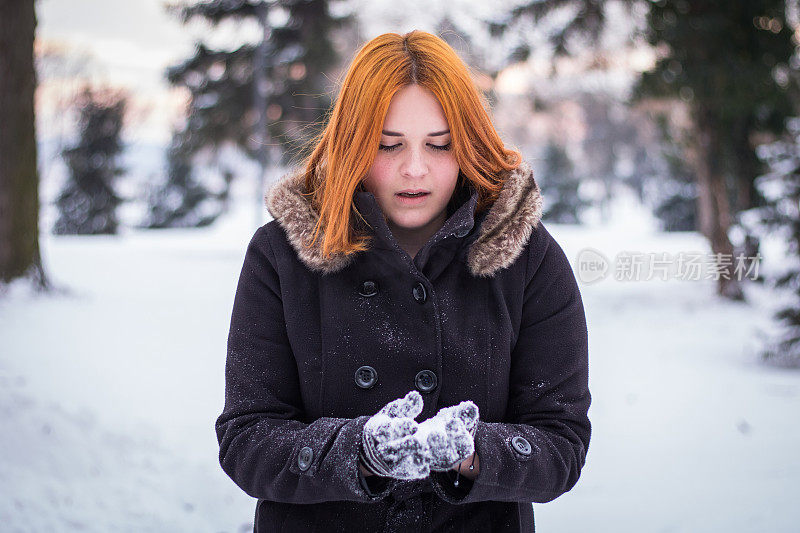 美丽的姜姑娘正在享受和玩雪。