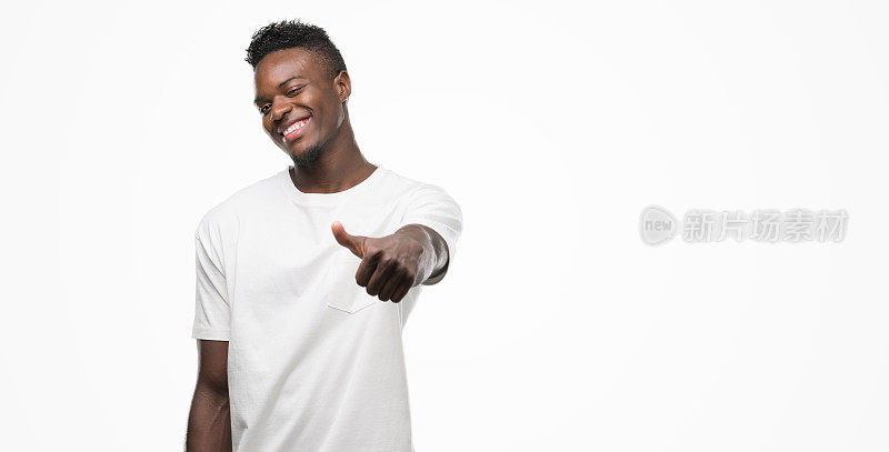 年轻的非洲裔美国人穿着白色t恤做快乐的拇指手势与手。赞许的表情看着镜头，表示成功。