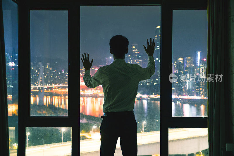 商人晚上站在窗边，用手触摸窗户