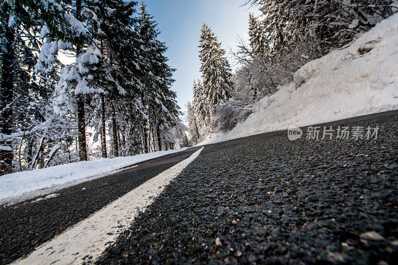 柏油路穿过积雪的冬季森林