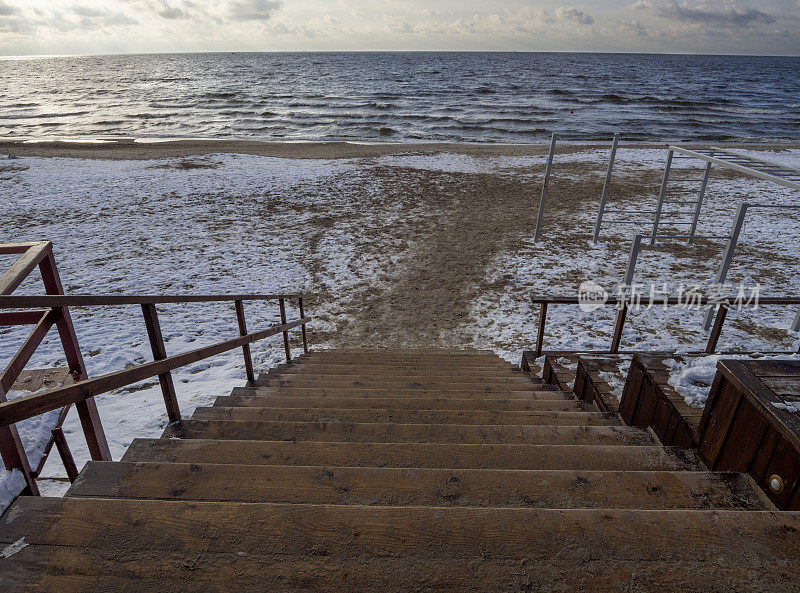 在一个阴天的冬天，立陶宛的克莱佩达，沿着木制的台阶走到波罗的海的沙滩上